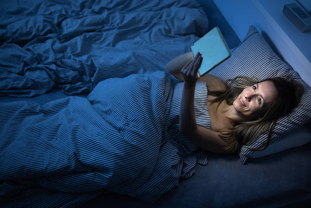 Pretty, middle-aged woman using her tablet computer before sleep - Foto, Bild