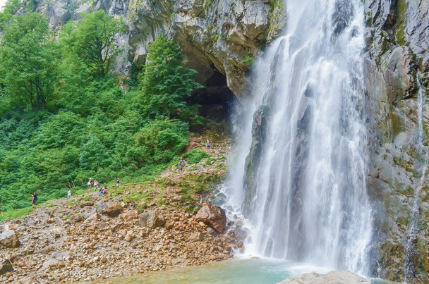 Gega waterval in de bergen van Abchazië. Een groep mensen ernaast.. - Foto, afbeelding