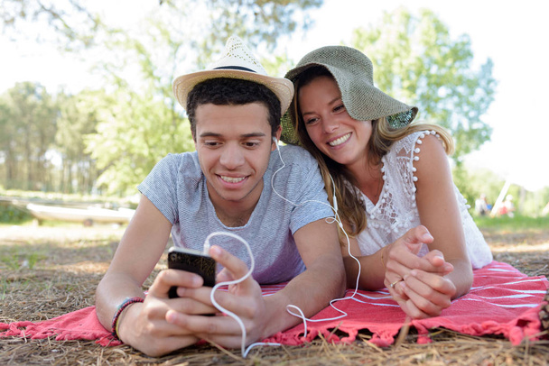 pareja joven acostada en un parque escuchando música
 - Foto, imagen