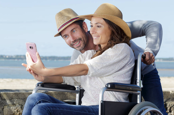couple by the beach in wheelchair taking selfie - Foto, Imagem