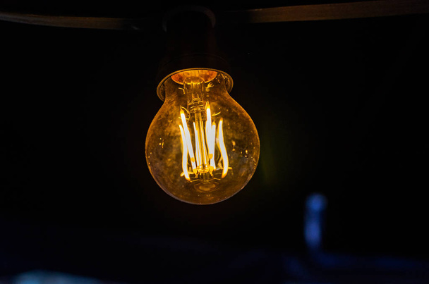 Incandescent light bulb illuminates the dark - Фото, зображення