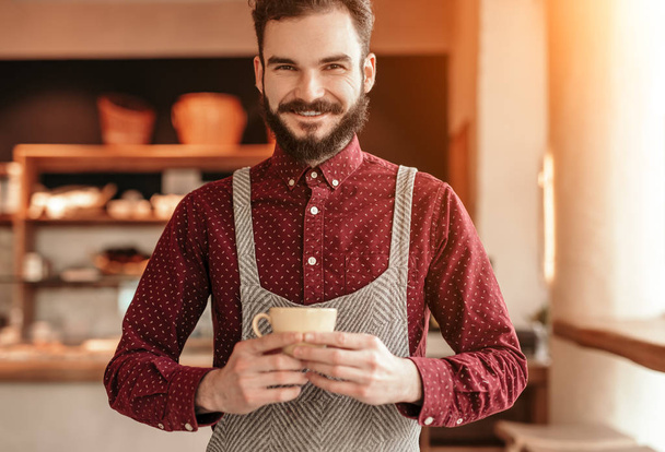 Friendly barista with cup of hot beverage - Photo, Image