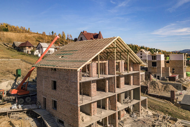 Marco de madera de techo nuevo en una casa grande de ladrillo en construcción
 - Foto, imagen