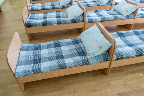 Many small beds with fresh linen in daycare preschool empty bedr - Foto, Bild