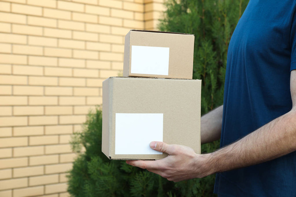 Delivery man hold blank boxes outdoor, space for text - Photo, Image