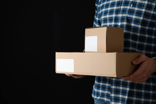 Hombre en camisa mantenga cajas en blanco contra fondo negro, espacio fo
 - Foto, imagen