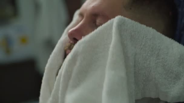 Close up of barbers hands drying mans beard with white towel in barbershop in slow motion.  - Materiał filmowy, wideo