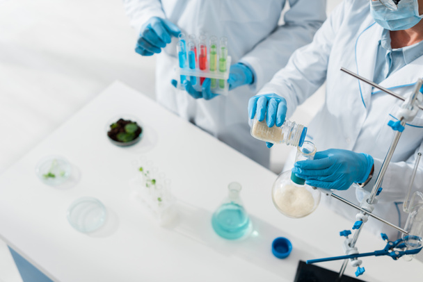vista recortada de biólogos con batas blancas haciendo pruebas en laboratorio
   - Foto, Imagen