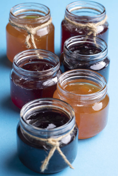 Canning jars with jam. Berry jams on blue paper - Photo, Image