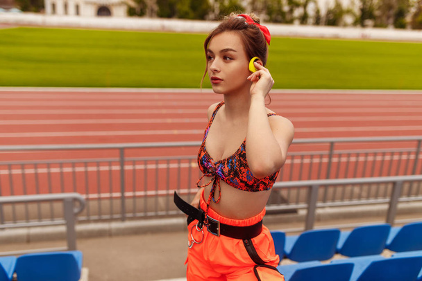 Confident female athlete listening to music on stadium - Fotoğraf, Görsel