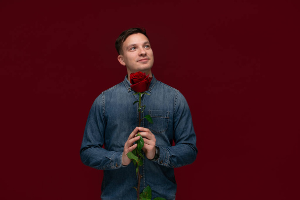 junger hübscher Mann, der eine rote Rose in der Hand hält, um sie seiner Geliebten zu schenken. Romantik - Foto, Bild