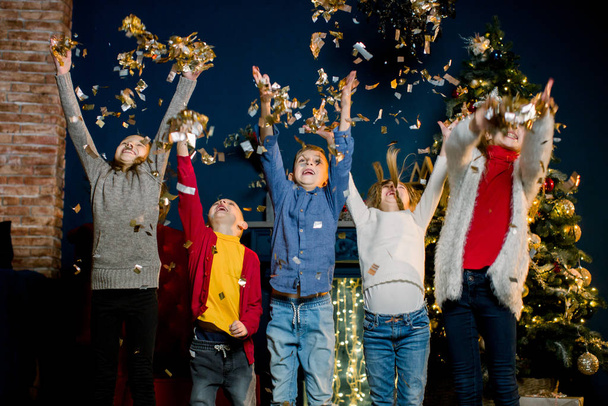Happy little five Caucasian kids throw confetti and celebrating Christmas. Winter holidays and New Year concept. - Foto, Imagen