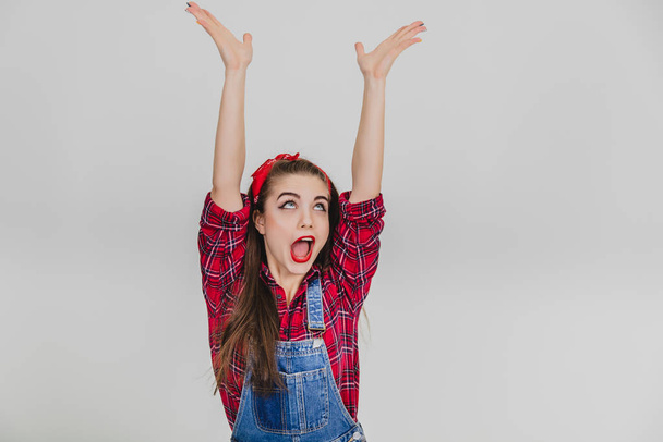 Extremely happy stylish girl in red is raising her hands, bouncing joyfully, shouting hurray. - Foto, Imagen
