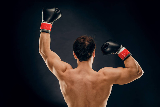 Achteraanzicht van man bokser met opgeheven handen in overwinningsgebaar. Aankondiging - Foto, afbeelding