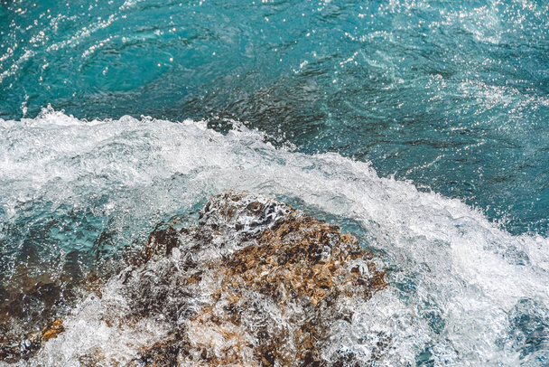 Hegyi folyó kővel a kék vízben. A tengeri dagály türkiz hullámai - Fotó, kép