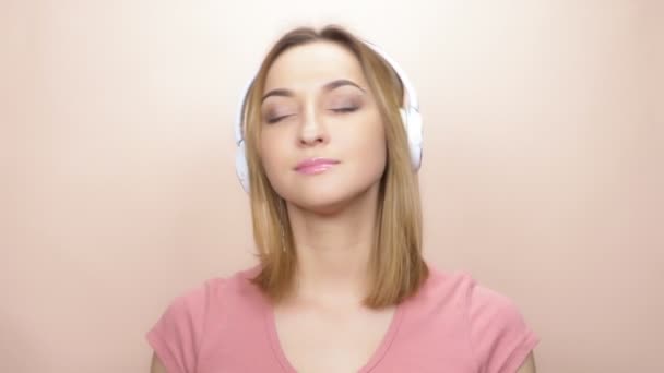 girl with pierced eyebrow and big eyes with headphones on a colored background - Πλάνα, βίντεο