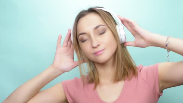 girl with pierced eyebrow and big eyes with headphones on a colored background - Materiał filmowy, wideo