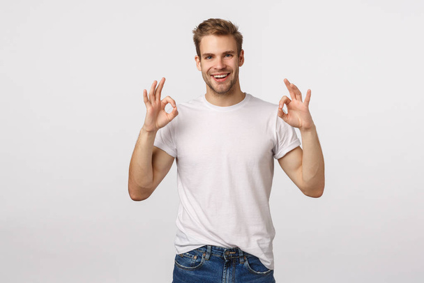 Man give approval. Pleased and happy smiling blond guy with bristle, show okay gestures, OK sign in approval, give confirmation, accept plan, praise amazing work, standing white backgound impressed - 写真・画像