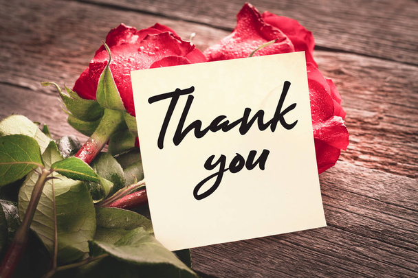 Nahaufnahme mit den Worten "Danke" auf einem Strauß roter Rosen auf einem hölzernen Hintergrund: das Konzept der Dankbarkeit und Wertschätzung - Foto, Bild