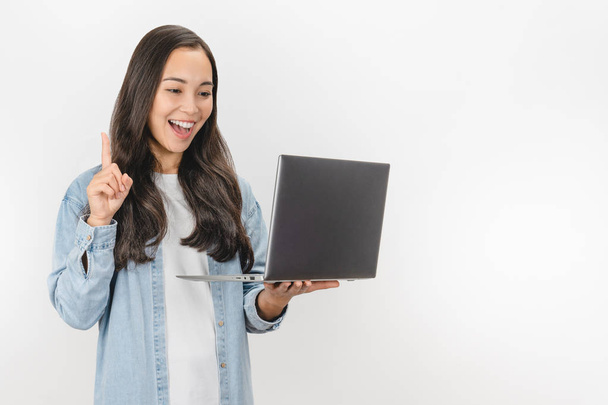 Kuva aasialainen innoissaan nuori nainen, jolla on idea poseeraa yli valkoinen seinä tausta kannettavan tietokoneen
 - Valokuva, kuva