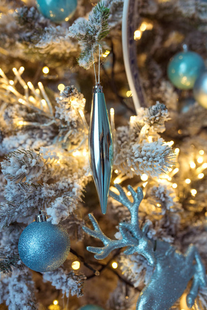 όμορφη μπλε και ασημένια χριστουγεννιάτικα στολίδια σε χριστουγεννιάτικο δέντρο σε φόντο γιρλάντα - Φωτογραφία, εικόνα