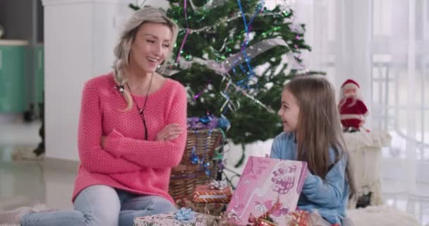 Positive Caucasian blond mother talking to daughter as child looking into gift box. Happy girl receiving Christmas present from mom. Enjoyment, holidays, New Years eve. Cinema 4k ProRes HQ. - Filmati, video