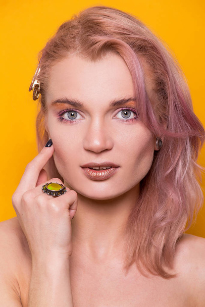 Shiny golden make-up on a beautiful young European model girl isolated on an orange background in the photo studio - 写真・画像