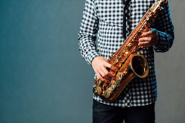 saxophone in hands close-up on blue uniform background - Foto, afbeelding