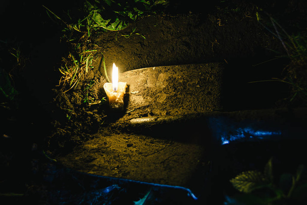 dirty old shovel in dark trench. Digging grave by candlelight. Mystical night scene - 写真・画像
