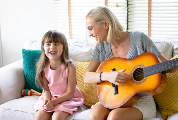 Music is so much fun. Mother and daughter playing guitar togethe - Fotó, kép