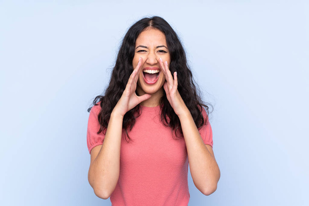 Mixed race woman wearing a sweater over isolated blue background shouting with mouth wide open - Fotografie, Obrázek