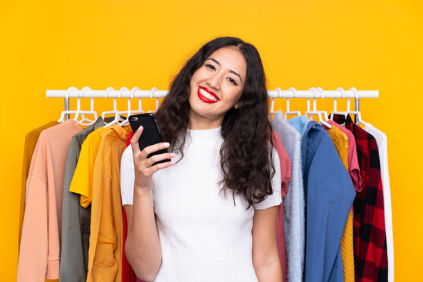 Змішана раса жінка в магазині одягу і розмовляє з мобільним
 - Фото, зображення