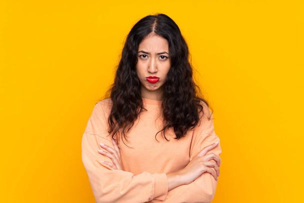 Spanish Chinese woman over isolated yellow background feeling upset - Фото, изображение