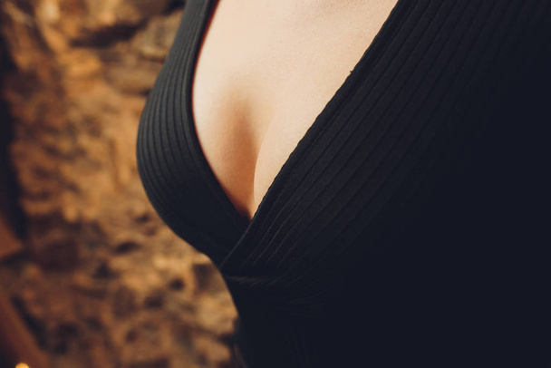 Decollete, female breast. Neckline black dress and fur collar. - Photo, Image