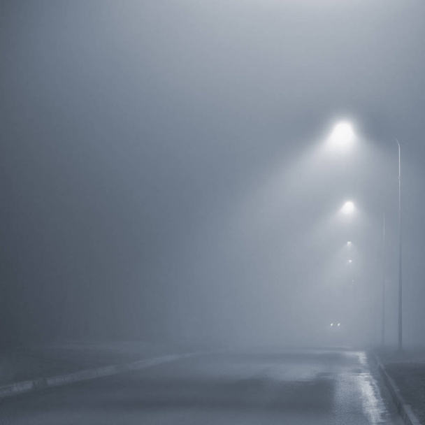 oświetlenie uliczne, mglistej nocy, Lampa po latarnie, opustoszałej drodze w mglisty mgła mokry asfalt asfalt, reflektory samochodu zbliża, pionowe, niebieski klawisz - Zdjęcie, obraz