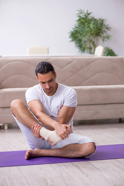 Leg injured man doing exercises at home - Foto, afbeelding