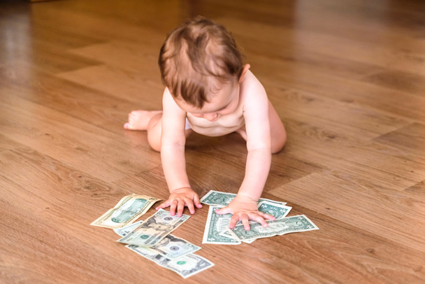 Младенец ползает по полу в поисках денег и находит доллар
  - Фото, изображение