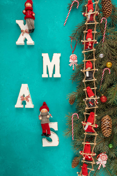Joulun tausta oksat joulukuusi, seppele punaisia nukkeja sinisellä pohjalla. ylhäältä. Uusi vuosi. XMAS puinen kirjoitus. Joulun kokoonpano
 - Valokuva, kuva