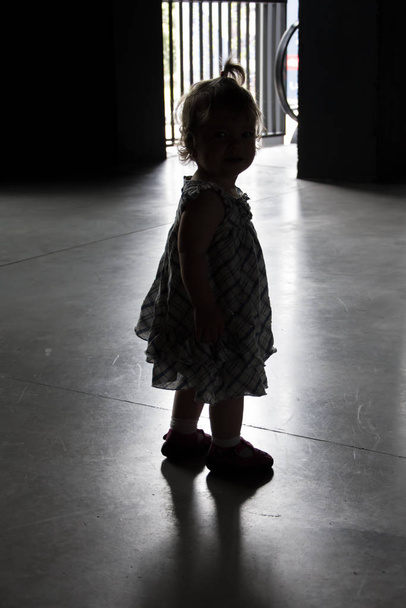Η σιλουέτα ενός μικρού κοριτσιού που άφησαν οι γονείς της σε ένα καταφύγιο. Έννοια: εγκαταλελειμμένα και χαμένα παιδιά, ορφανά και μοναξιά. - Φωτογραφία, εικόνα