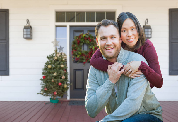 Chinesische und kaukasische junge erwachsene Paar auf Weihnachten dekoriert Veranda des Hauses. - Foto, Bild