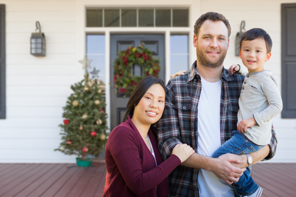 Parents chinois et caucasiens mixtes avec enfant sur le porche avant décoré de Noël
 - Photo, image
