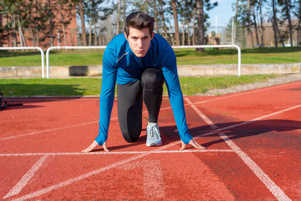 Man athlete on the starting line of a running track at the stadium. - Photo, Image