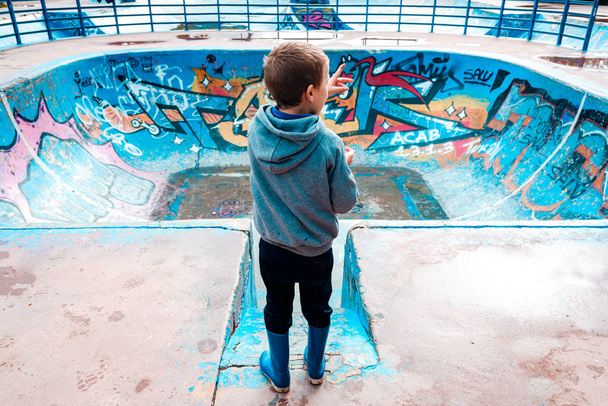 Child loitering inside an abandoned skating area, painted blue,  - Photo, Image