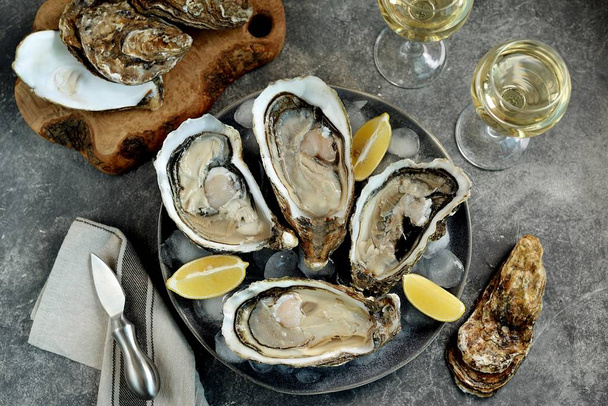 Reuzenverse ongekookte oesters in een schaal met citroen op ijs. Gezond voedsel. - Foto, afbeelding