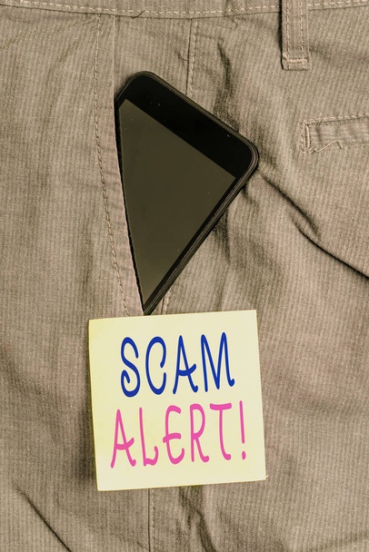 Word writing text scam alarm. Geschäftskonzept für betrügerische Erlangung von Geld von Opfer durch Überredung Smartphone-Gerät in formale Arbeitshose Fronttasche in der Nähe von Zettelpapier. - Foto, Bild