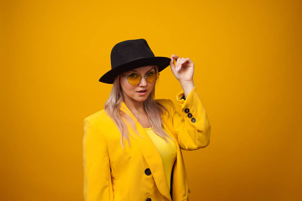 Cheerful trending young woman in bright clothes on yellow background, copy space. Cool blonde - Фото, изображение