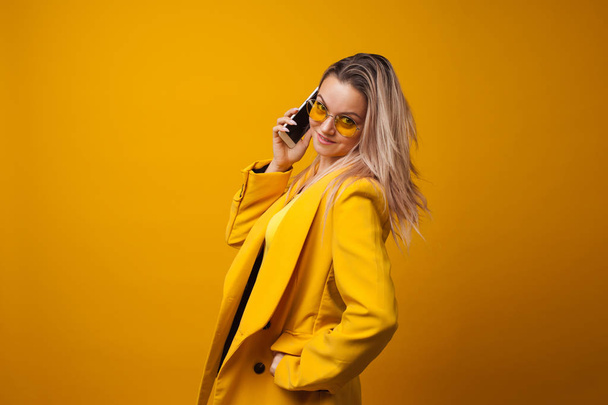 Stylish positive young woman on yellow background, copy space. - Foto, imagen