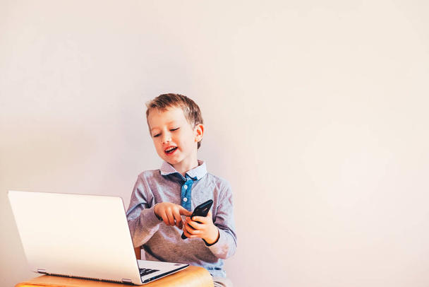 Bambino con un viso molto espressivo che lavora di fronte a un computer portatile w
 - Foto, immagini