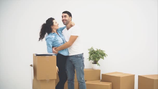 A fiatal pár új lakásba költözik. Ölelkező és ölelkező pár. Észrevettek néhány papírt a dobozokon, és egy quintet kapnak velük. 4k. - Felvétel, videó
