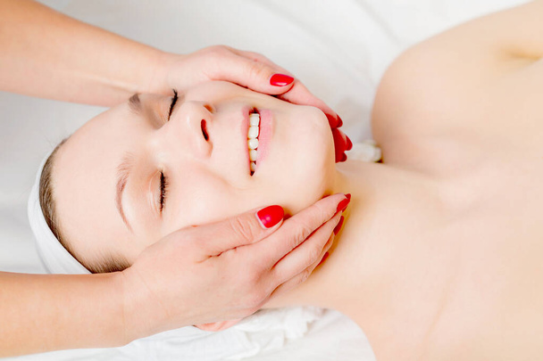 Красива молода жінка отримує масаж обличчя з закритими очима
  - Фото, зображення